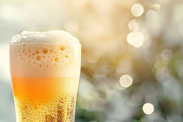 Closeup of a cold glass of beer with a foam head against a bokeh background